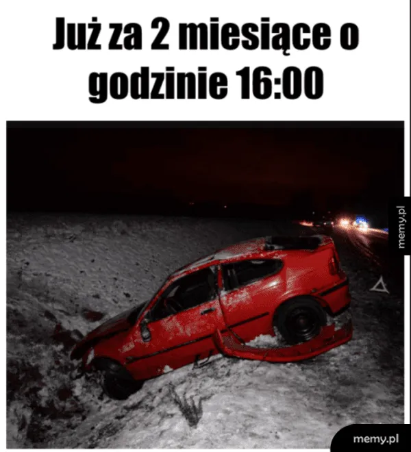 Rozbity czerwony samochód w rowie zimą w nocy