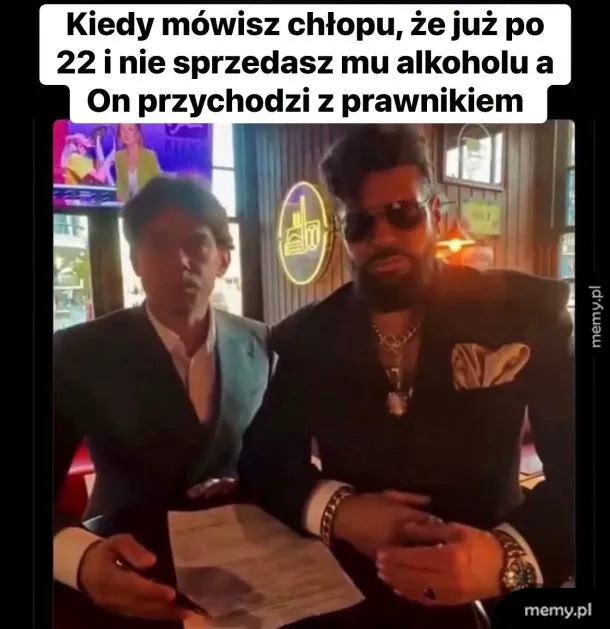 Dwóch eleganckich mężczyzn w garniturach siedzi przy stoliku z dokumentami.